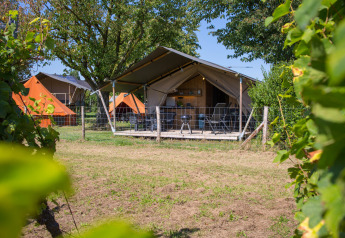 Tienda safari con instalaciones sanitarias en Camping de Boomgaard, Bélgica, rodeada de vegetación.