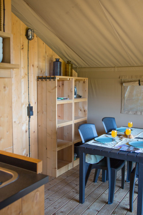 Innenansicht eines Safarizeltes mit Sanitäranlagen auf Camping de Boomgaard, Belgien, mit Esstisch.