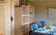 Inside a safari tent with sanitary facilities at Camping de Boomgaard, Belgium, showing dining area.