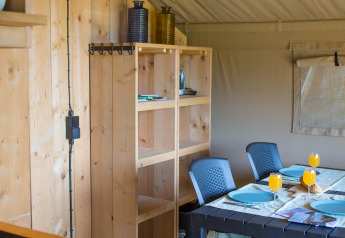 Inside a safari tent with sanitary facilities at Camping de Boomgaard, Belgium, showing dining area.