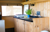 Vista interior de la cocina de una tienda safari con armarios de madera en Camping de Boomgaard, Bélgica.
