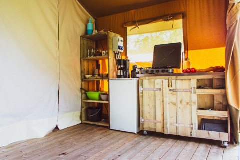 Coin cuisine en bois avec réchaud, frigo et étagères dans une tente safari au Camping de Boomgaard en Belgique.