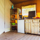 Cozy wooden kitchen setup with stove, fridge and shelves inside a safari tent at Camping de Boomgaard, Belgium.