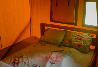 Vista interna di una tenda safari con letto matrimoniale e finestre, Safari tent al Camping du Rivage in Lussemburgo.