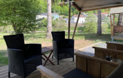 View from a safari tent terrace at Camping du Rivage in Luxembourg with outdoor chairs and greenery.
