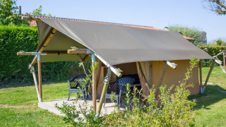 Tienda safari Duo Lodge en Camping de Boomgaard, Bélgica, estructura de madera y sillas exteriores.