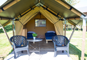 Tienda safari Duo Lodge en Camping de Boomgaard, Bélgica, con dos camas, sillas y mesa exterior.