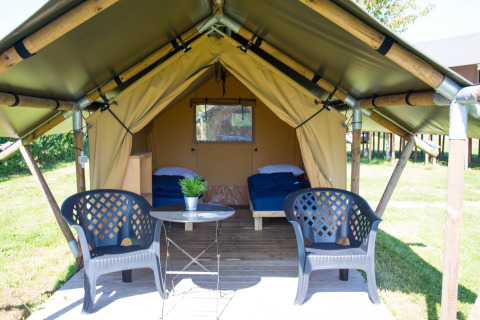 Safari-Zelt Duo Lodge auf Camping de Boomgaard in Belgien mit Doppelbett, Stühlen und Tisch draußen.