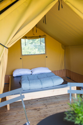 Vista interior de una tienda safari Duo Lodge en Camping de Boomgaard en Bélgica con una cama doble.