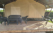 Buitenzitje van een safaritent op Camping de Oude Rijn in Nederland, met kunststof tuinmeubelen op terras.