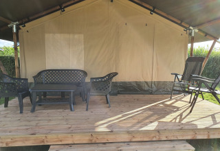 Área de estar exterior de una tienda safari en Camping de Oude Rijn, Países Bajos, con muebles de plástico.