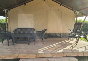Área de estar exterior de una tienda safari en Camping de Oude Rijn, Países Bajos, con muebles de plástico.
