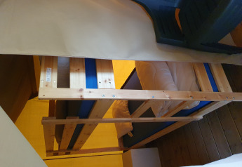 Litera de madera con colchones azules en el interior de una tienda safari en Camping de Oude Rijn, Países Bajos, vista lateral.