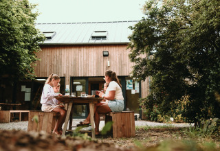 Gezin aan het eten aan een houten tafel bij Feather Down Les Jardins des Coccinelles in Bretagne, Frankrijk.