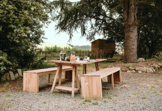 Picknicktisch mit Bänken und Frühstück am Feather Down Les Jardins des Coccinelles in der Bretagne, Frankreich.