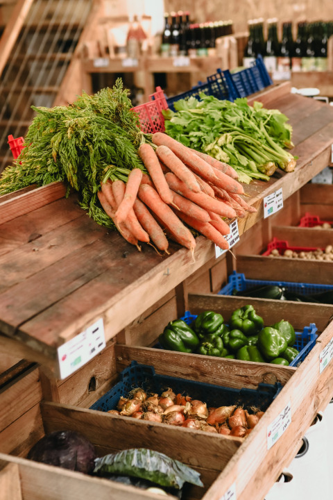 Frisches Gemüse wie Karotten und Paprika werden auf einem Markt bei Feather Down Les Jardins des Coccinelles ausgestellt.