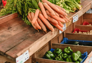 Friske grøntsager som gulerødder og peberfrugter vises på et marked hos Feather Down Les Jardins des Coccinelles.