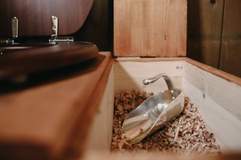 Primer plano de un inodoro de compostaje con virutas de madera y pala de metal en Feather Down Les Jardins des Coccinelles, Bretaña.