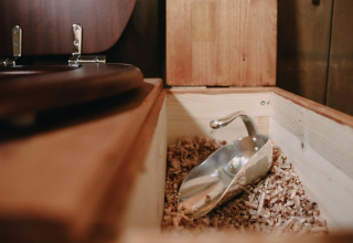 Nahaufnahme einer Komposttoilette mit Holzspänen und Metallschaufel im Feather Down Les Jardins des Coccinelles in der Bretagne.