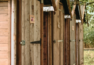 Row of rustic wooden outdoor toilet doors at Feather Down Les Jardins des Coccinelles, Brittany, France.