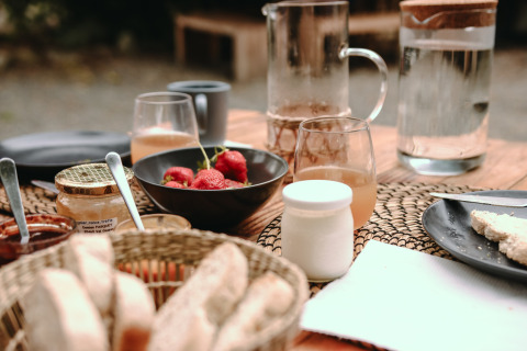 Desayuno en Feather Down Les Jardins des Coccinelles con pan, fresas, miel y bebidas refrescantes.