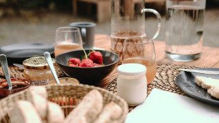 Desayuno en Feather Down Les Jardins des Coccinelles con pan, fresas, miel y bebidas refrescantes.