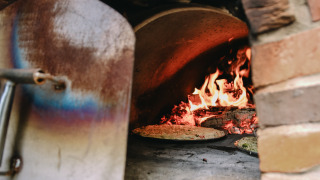 Un horno de leña con pizzas cocinándose y llamas ardiendo, en Feather Down Les Jardins des Coccinelles.