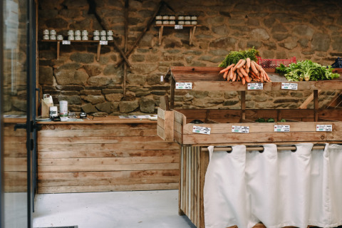 Indoor vegetable stall with fresh carrots and greens in wooden crates at Feather Down, Brittany, France.