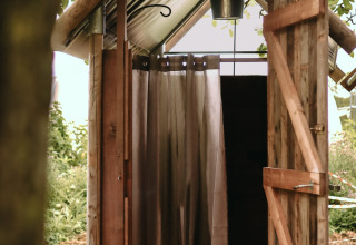 Doccia all'aperto in una rustica capanna di legno presso Feather Down Les Jardins des Coccinelles, Bretagna, Francia.