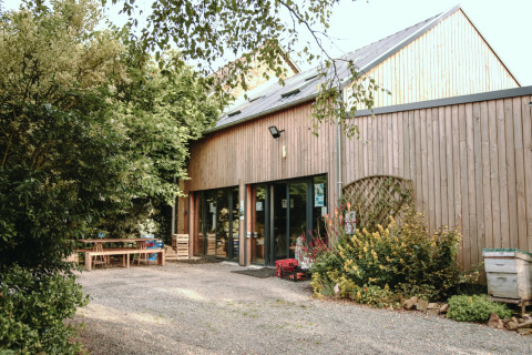 Et træbeklædt feriehus med store vinduer og have ved Feather Down Les Jardins des Coccinelles i Bretagne, Frankrig.