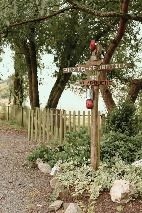 Wooden signpost at Feather Down Les Jardins des Coccinelles holiday park in Brittany, France, among lush greenery.