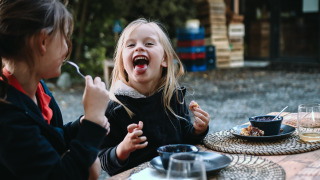 Dos niños disfrutan de una comida al aire libre en Feather Down Les Jardins des Coccinelles en Bretaña, Francia.