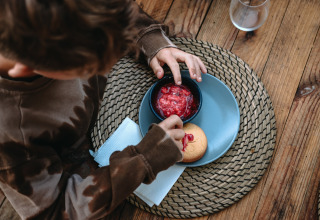 Bambino intinge un biscotto nella marmellata di fragole a Feather Down Les Jardins des Coccinelles, Bretagna.