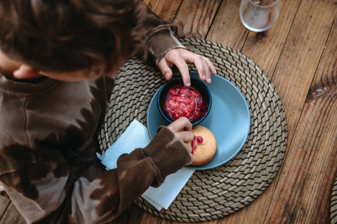 Niño sumerge una galleta en mermelada de fresa durante las vacaciones en Feather Down en Bretaña, Francia.
