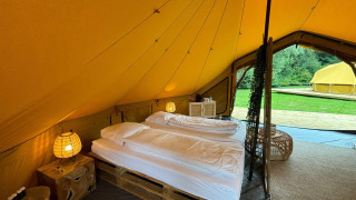 Innenaufnahme eines Safari-Zeltes mit Doppelbett und stilvoller Einrichtung im Urban-Gardens Bivak Deluxe, Belgien.