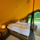 Vista interna di una tenda safari di lusso con letto matrimoniale e arredi accoglienti a Urban-Gardens, Belgio.