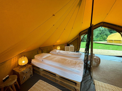 Interieur van een luxe safaritent met tweepersoonsbed en gezellige inrichting bij Urban-Gardens Bivak Deluxe, België.