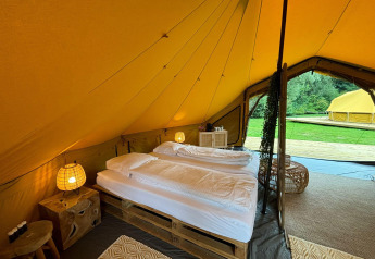 Interior view of a luxury safari tent with double bed and cozy decor at Urban-Gardens Bivak Deluxe, Belgium.