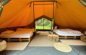 Interno di una tenda safari di lusso con due letti matrimoniali su pallet e arredo naturale in Belgio.