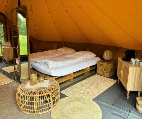 Interno della tenda safari Bivak Deluxe - Gent a Urban-Gardens in Belgio, con letto doppio e arredi naturali.
