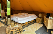 Interno della tenda safari Bivak Deluxe - Gent a Urban-Gardens in Belgio, con letto doppio e arredi naturali.