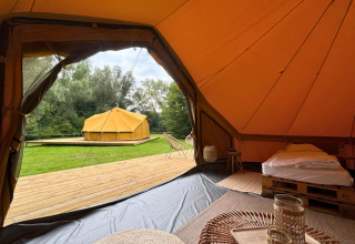 Binnenzicht van een safaritent met gezellig interieur, houten terras en tent op Urban-Gardens Gent in België.