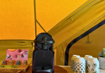 Koffiezetapparaat, kopjes en capsules op tafel in safaritent bij Bivak Deluxe - Gent, Urban-Gardens, België.