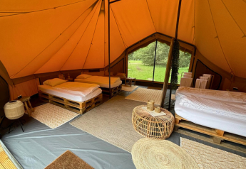 Interior of Bivak Deluxe - Gent safari tent at Urban-Gardens, Belgium, featuring beds and rustic decor.