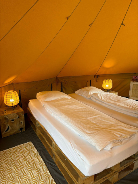 Interieur van Bivak Deluxe - Gent safaritent bij Urban-Gardens in België met twee bedden en sfeervolle verlichting.