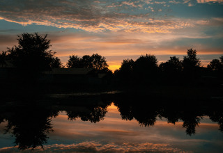 Hermoso atardecer sobre un lago reflejante en Tiny house en Holiday park Eigen Wijze, Países Bajos.