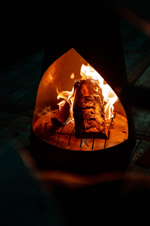 Brandende houtblokken in een haard bij de tiny house op Holiday park Eigen Wijze, Nederland, knusse sfeer.