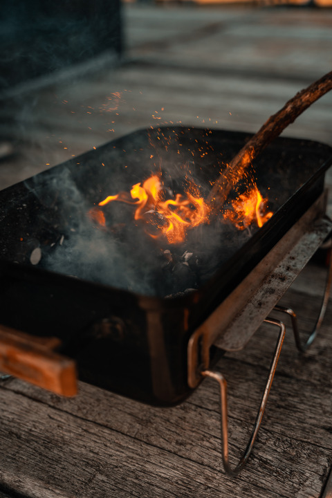 Fuego ardiendo en una parrilla portátil sobre una terraza de madera en la Tiny House de Holiday park Eigen Wijze, Países Bajos.