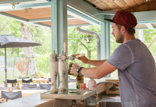 Uomo che spillando birra alla spina al bar esterno del Camping Pittoresque, villaggio vacanze in Occitania, Francia.