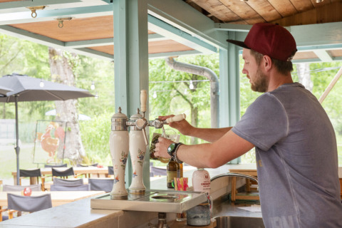 Uomo che spillando birra alla spina al bar esterno del Camping Pittoresque, villaggio vacanze in Occitania, Francia.